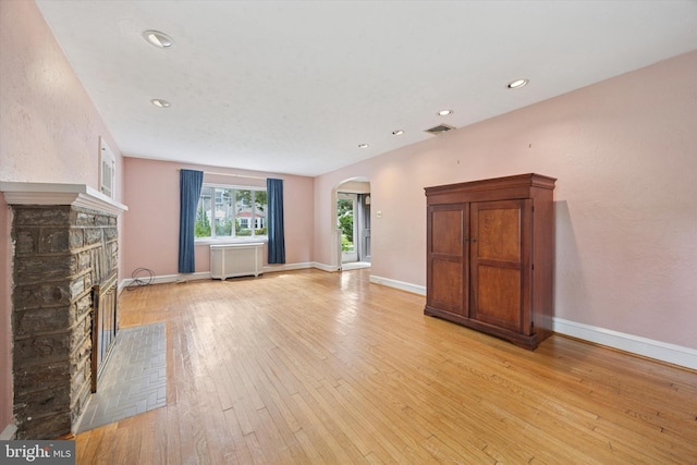 1100 Drexel Ave, Drexel Hill, PA 19026 - unfurnished living room featuring arched walkways, a stone fireplace, light wood-style floors, baseboards, and recessed lighting