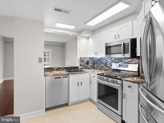 1045 N Utah St Unit 2-404, Arlington, VA 22201 - kitchen featuring stainless steel appliances, a sink, white cabinets, backsplash, and dark stone countertops