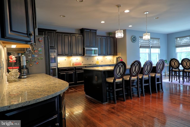 3348 Soaring Cir, Woodbridge, VA 22193 - kitchen with stainless steel appliances, a kitchen breakfast bar, decorative backsplash, a center island, and dark wood-type flooring
