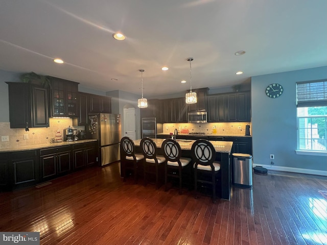 3348 Soaring Cir, Woodbridge, VA 22193 - kitchen with stainless steel appliances, a kitchen breakfast bar, tasteful backsplash, dark wood-style flooring, and glass insert cabinets