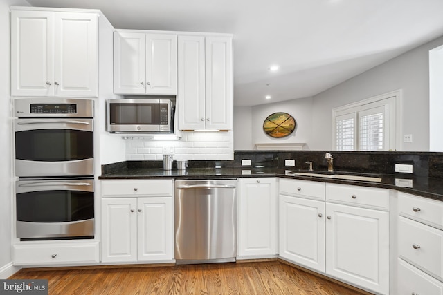 9630 Beman Woods Way, Potomac, MD 20854 - kitchen with stainless steel appliances, a sink, light wood-style floors, white cabinetry, and tasteful backsplash