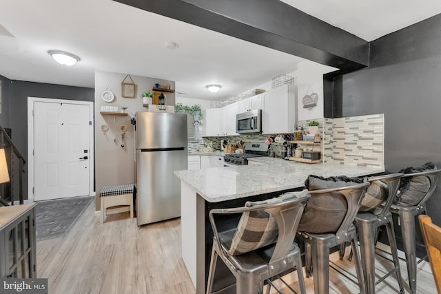 35 La Cascata, Clementon, NJ 08021 - kitchen with stainless steel appliances, a peninsula, white cabinetry, tasteful backsplash, and light wood-type flooring