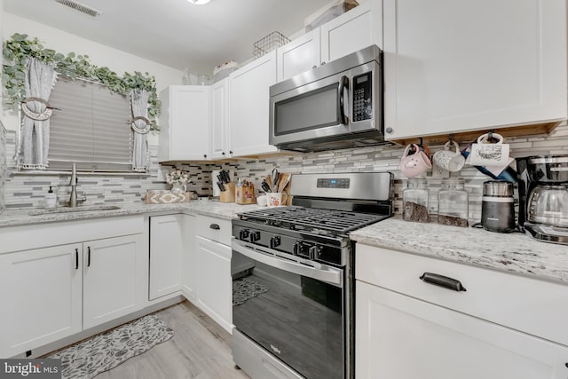 35 La Cascata, Clementon, NJ 08021 - kitchen featuring stainless steel appliances, a sink, tasteful backsplash, and white cabinets