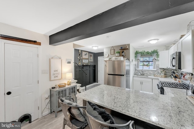 35 La Cascata, Clementon, NJ 08021 - kitchen with appliances with stainless steel finishes, light stone countertops, a peninsula, white cabinets, and light wood finished floors