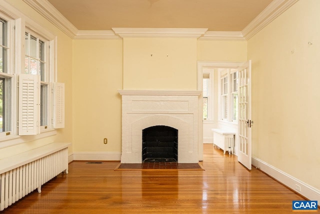 803 Alleghany Ave, Staunton, VA 24401 - unfurnished living room featuring radiator, crown molding, wood finished floors, a brick fireplace, and baseboards
