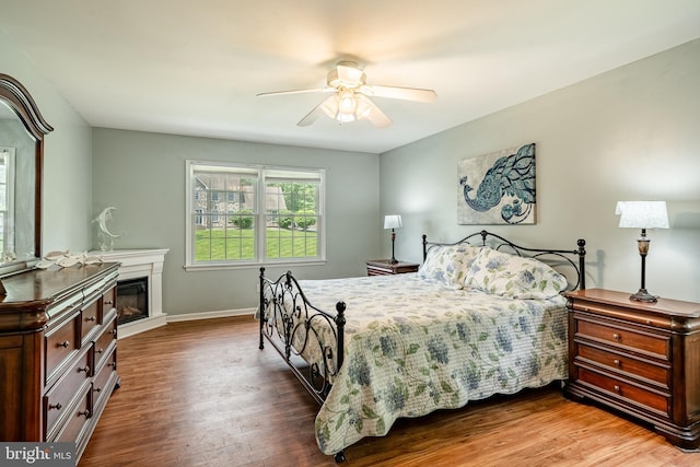 174 Greentree Dr, Bangor, PA 18013 - bedroom with wood finished floors, a glass covered fireplace, a ceiling fan, and baseboards