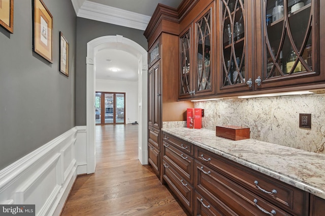 2555 Vale Ridge Ct, Oakton, VA 22124 - bar area featuring ornamental molding, arched walkways, wood finished floors, tasteful backsplash, and wainscoting
