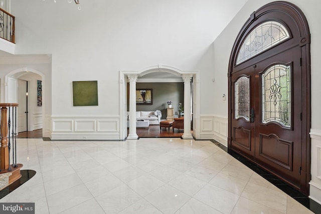 2555 Vale Ridge Ct, Oakton, VA 22124 - tiled entrance foyer featuring ornate columns, a towering ceiling, a decorative wall, arched walkways, and a wainscoted wall