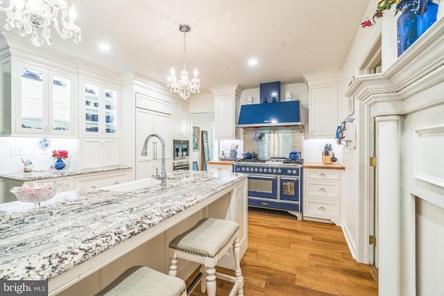 355 Arden, Gulph Mills, PA 19428 - kitchen with range with two ovens, a chandelier, a sink, white cabinetry, and light wood finished floors