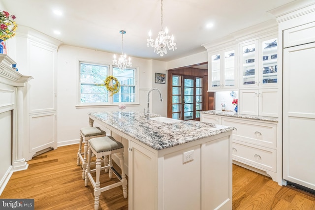 355 Arden, Gulph Mills, PA 19428 - kitchen featuring a sink, a chandelier, light wood-style flooring, white cabinetry, and glass insert cabinets