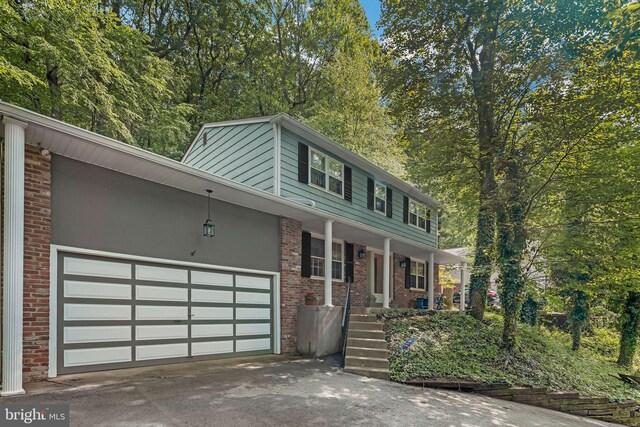355 Arden, Gulph Mills, PA 19428 - view of front of home featuring driveway, a porch, a garage, and brick siding