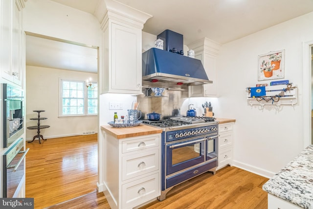 355 Arden, Gulph Mills, PA 19428 - kitchen with range with two ovens, exhaust hood, light wood-style floors, and white cabinetry