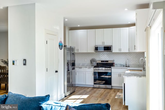 528 N Third St, Martinsburg, WV 25404 - kitchen with stainless steel appliances, a sink, tasteful backsplash, light wood-type flooring, and white cabinets