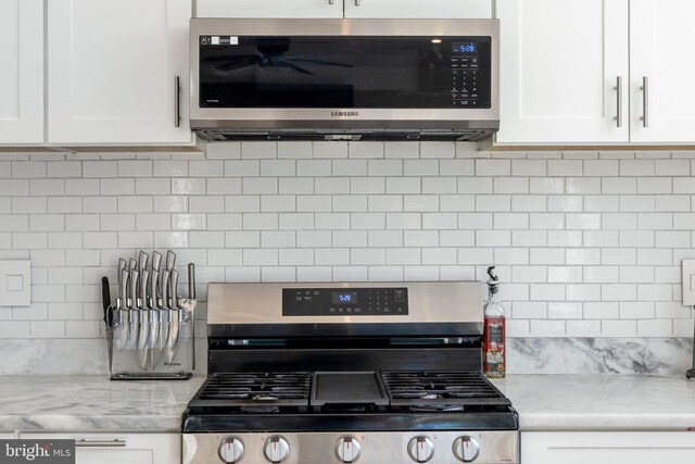 528 N Third St, Martinsburg, WV 25404 - kitchen featuring appliances with stainless steel finishes, tasteful backsplash, white cabinets, and light stone counters