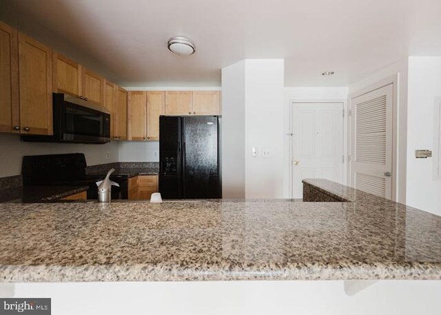 777 7th St NW Unit 913, Washington, DC 20001 - kitchen featuring black appliances, light stone counters, and a peninsula