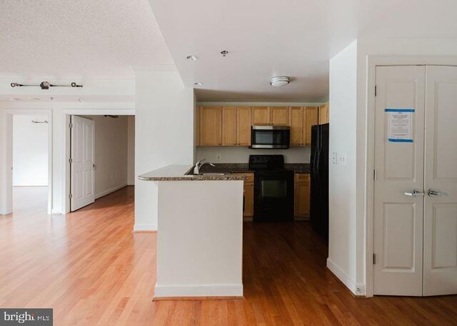 777 7th St NW Unit 913, Washington, DC 20001 - kitchen featuring black appliances, a peninsula, light wood-type flooring, and baseboards