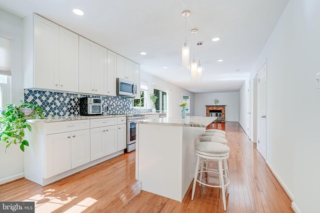 1434 Cellar Creek Way, Herndon, VA 20170 - kitchen with appliances with stainless steel finishes, light wood-style flooring, a kitchen island, backsplash, and white cabinets