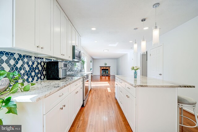 1434 Cellar Creek Way, Herndon, VA 20170 - kitchen featuring stainless steel appliances, light wood-style flooring, white cabinets, a kitchen breakfast bar, and recessed lighting