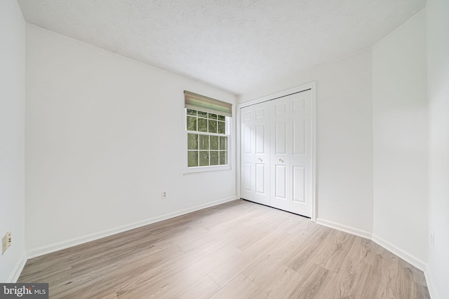 1434 Cellar Creek Way, Herndon, VA 20170 - unfurnished bedroom featuring light wood-type flooring, baseboards, a closet, and a textured ceiling