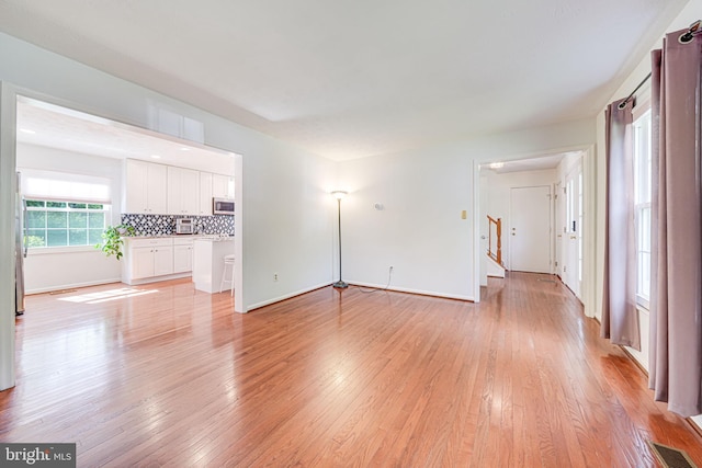 1434 Cellar Creek Way, Herndon, VA 20170 - unfurnished living room with light wood-style flooring, stairway, and baseboards