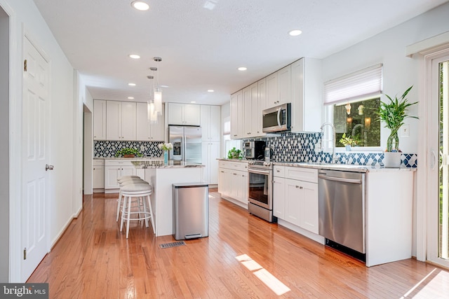 1434 Cellar Creek Way, Herndon, VA 20170 - kitchen with stainless steel appliances, a kitchen breakfast bar, light wood-style flooring, white cabinetry, and recessed lighting