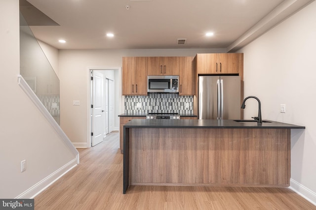 4096 Conshohocken Ave Unit A2, Philadelphia, PA 19131 - kitchen with appliances with stainless steel finishes, dark countertops, a sink, light wood-style floors, and a peninsula