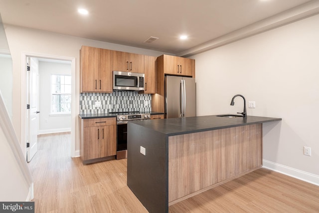 4096 Conshohocken Ave Unit A2, Philadelphia, PA 19131 - kitchen with stainless steel appliances, a sink, dark countertops, a peninsula, and backsplash