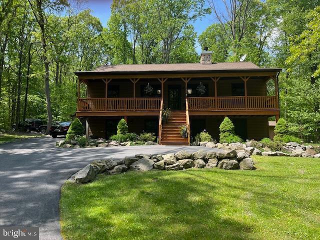 2733 Wood Ln, Morgantown, PA 19543 - view of front of property with a porch, a chimney, stairway, a front lawn, and asphalt driveway