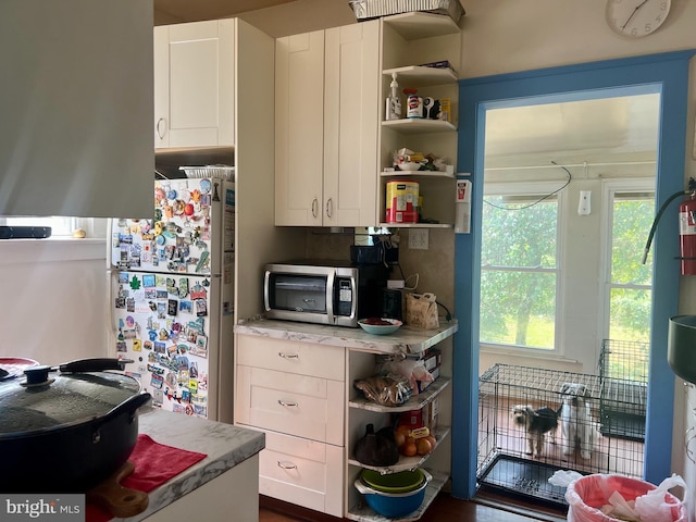 3706 36th St, Mount Rainier, MD 20712 - kitchen with open shelves, stainless steel microwave, freestanding refrigerator, and white cabinets