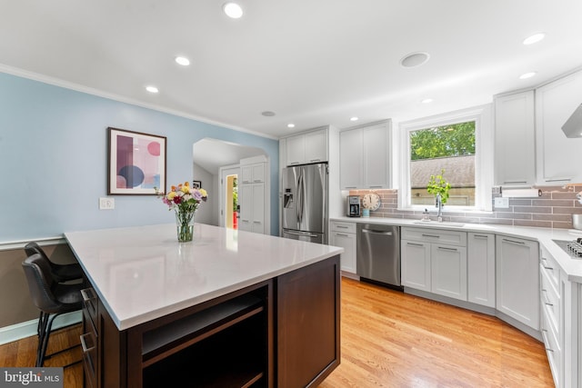 1110 Clover Hill Rd, Wynnewood, PA 19096 - kitchen with stainless steel appliances, a sink, backsplash, crown molding, and light wood-style flooring