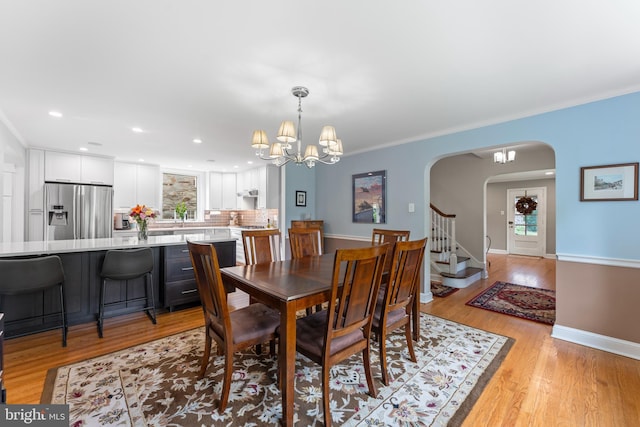 1110 Clover Hill Rd, Wynnewood, PA 19096 - dining space with arched walkways, light wood finished floors, a chandelier, crown molding, and baseboards