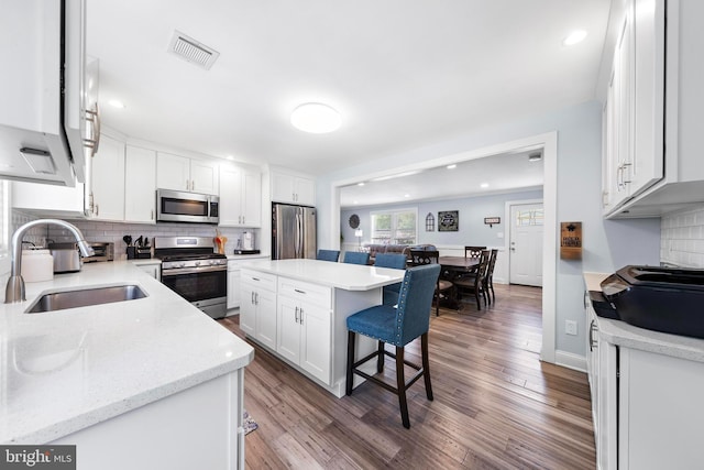 420 Conifer Dr, Forked River, NJ 08731 - kitchen with stainless steel appliances, a sink, white cabinets, wood finished floors, and a kitchen breakfast bar