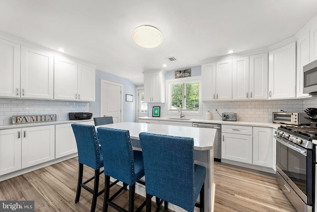 420 Conifer Dr, Forked River, NJ 08731 - kitchen with stainless steel appliances, a breakfast bar, a sink, decorative backsplash, and light countertops