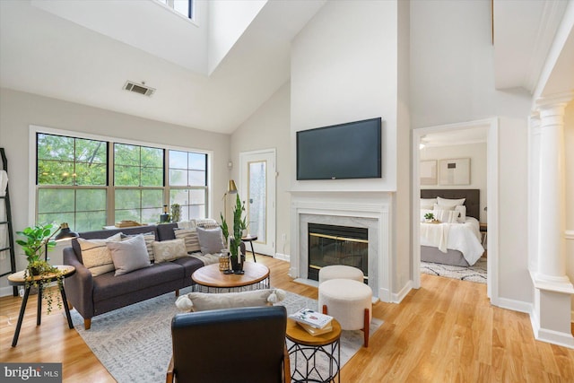 6832 Hayley Ridge Way Unit C, Baltimore, MD 21209 - living room featuring ornate columns, high vaulted ceiling, light wood-style floors, a premium fireplace, and baseboards