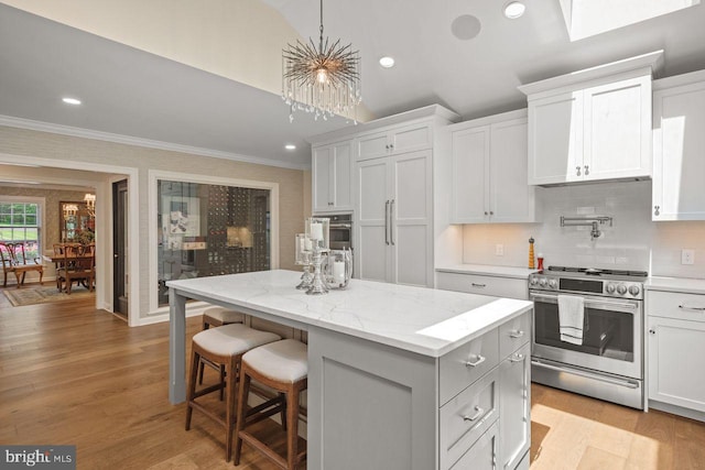121 Eshelman Rd, Lancaster, PA 17601 - kitchen featuring stainless steel gas stove, crown molding, a center island, light wood-type flooring, and backsplash