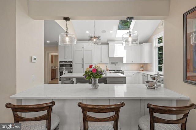 121 Eshelman Rd, Lancaster, PA 17601 - kitchen featuring a peninsula, double oven, backsplash, white cabinetry, and a breakfast bar area
