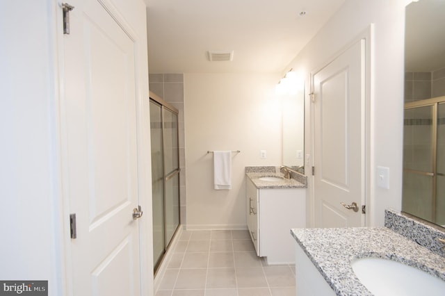 305 Shipyard Dr Unit 61, Cambridge, MD 21613 - bathroom featuring two vanities, a stall shower, tile patterned flooring, and baseboards