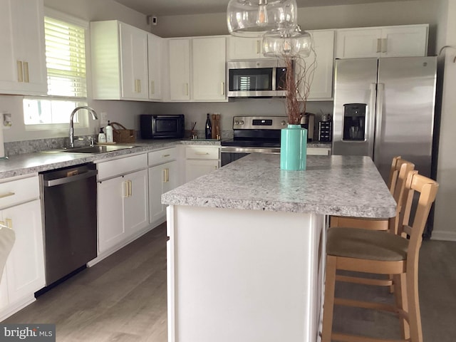 212 Bowline Dr, Cambridge, MD 21613 - kitchen with stainless steel appliances, a sink, a kitchen island, white cabinetry, and a kitchen breakfast bar