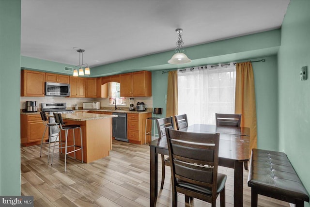 69 Calais Dr, Reading, PA 19605 - kitchen featuring appliances with stainless steel finishes, a center island, light wood finished floors, hanging light fixtures, and a kitchen breakfast bar