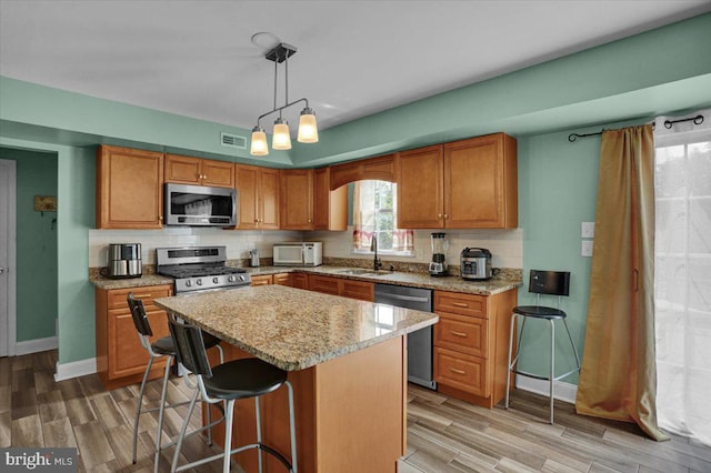 69 Calais Dr, Reading, PA 19605 - kitchen with stainless steel appliances, a sink, light wood finished floors, a breakfast bar, and brown cabinetry