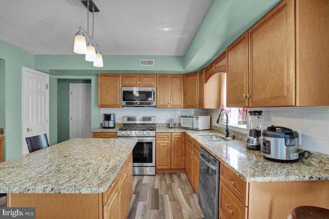 69 Calais Dr, Reading, PA 19605 - kitchen featuring appliances with stainless steel finishes, a sink, decorative backsplash, light wood-type flooring, and light stone countertops