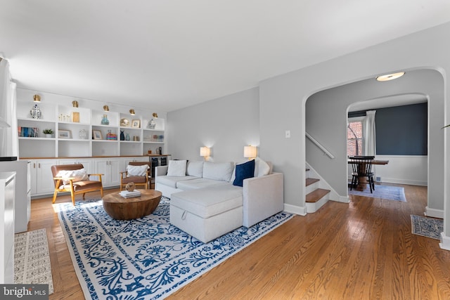 812 E Haverford Rd, Bryn Mawr, PA 19010 - living room featuring arched walkways, stairs, light wood-type flooring, and baseboards