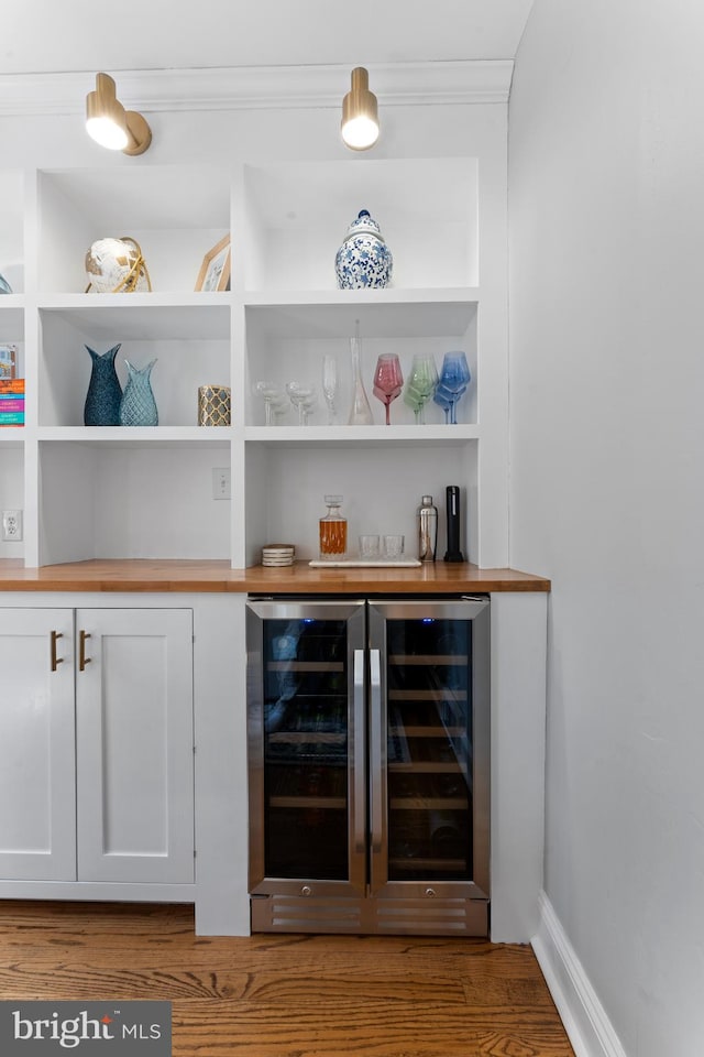 812 E Haverford Rd, Bryn Mawr, PA 19010 - indoor dry bar featuring beverage cooler, wood finished floors, crown molding, and built in shelves