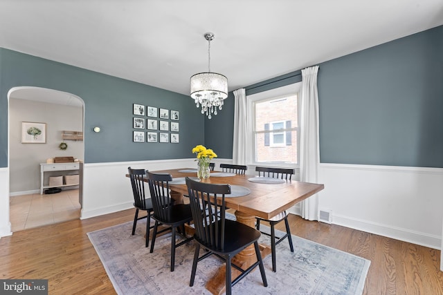 812 E Haverford Rd, Bryn Mawr, PA 19010 - dining area featuring wood finished floors, a chandelier, arched walkways, and baseboards