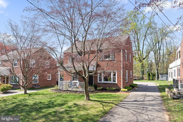 812 E Haverford Rd, Bryn Mawr, PA 19010 - traditional-style house with brick siding, covered porch, a front lawn, and a chimney