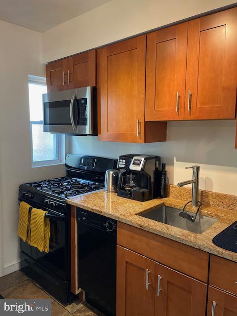 3936 NE Blaine St NE, Washington, DC 20019 - kitchen with black appliances, a sink, light stone counters, and brown cabinetry