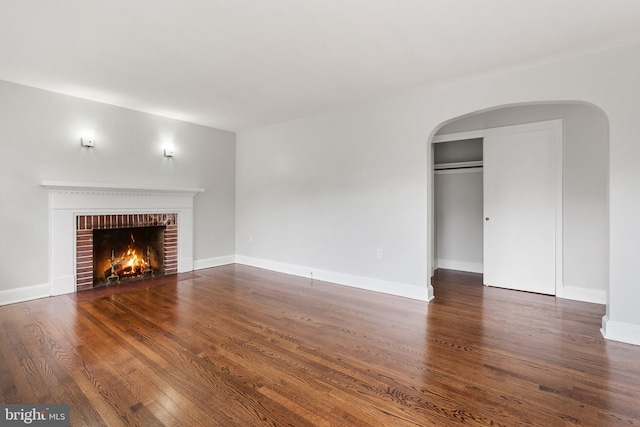 509 W Cork St, Winchester, VA 22601 - unfurnished living room featuring arched walkways, wood finished floors, a fireplace, and baseboards