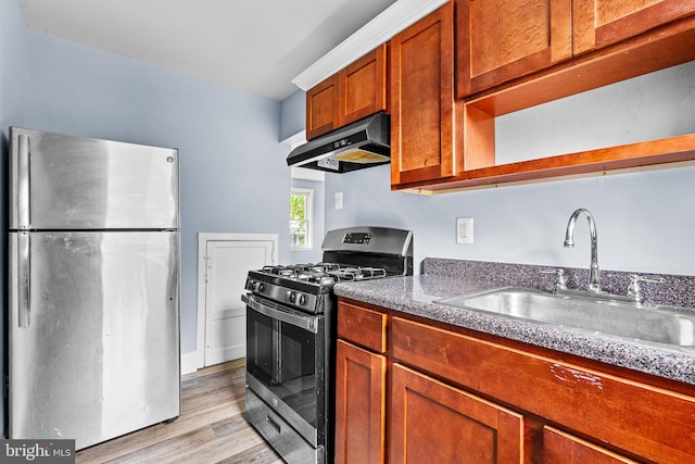 821 E Jeffrey St, Baltimore, MD 21225 - kitchen with appliances with stainless steel finishes, under cabinet range hood, a sink, light wood-style flooring, and brown cabinetry