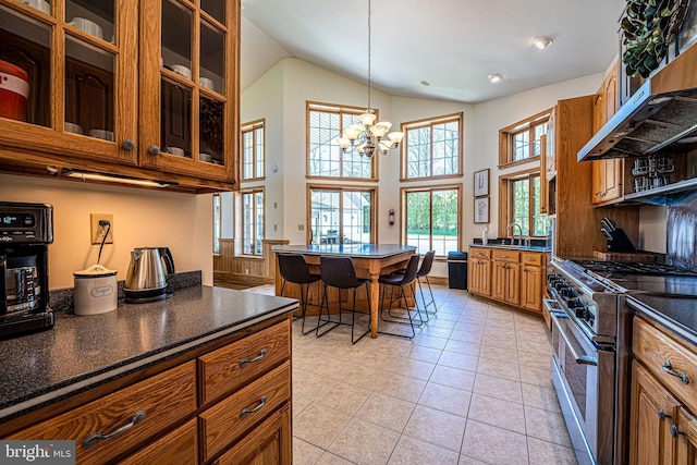 1874 Roundtop Rd, Wellsboro, PA 16901 - kitchen with stainless steel stove, under cabinet range hood, dark countertops, brown cabinets, and a chandelier
