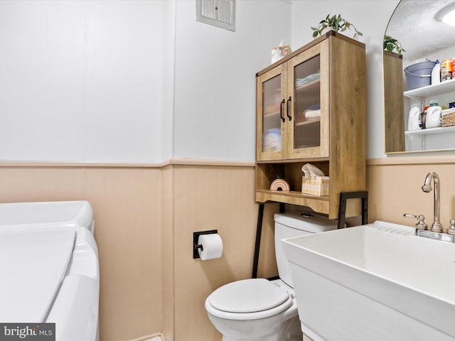 25 E Potomac St, Williamsport, MD 21795 - half bathroom featuring washing machine and clothes dryer, toilet, a wainscoted wall, and a sink